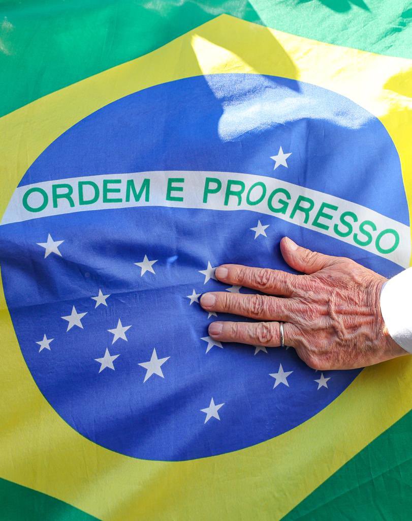 Fotografia da mão de Lula da Silva sobre a bandeira do Brasil